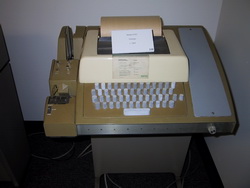 《圖二　打孔紙之後是電傳機，稱為Electromechanical Teleprinter或TeleTYpewriter（簡稱：TTY，電傳打字機），輸入用打字，輸出用列印，以此與電腦溝通。》