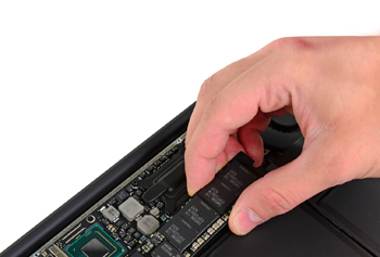 《圖二  新款MacBook Air內使用mSATA標準的SSD固態硬碟（手拿者），Wi-Fi模組（綠色晶片組左下相鄰）也以內埋方式處理。（圖片來源：iFixIt.com）》