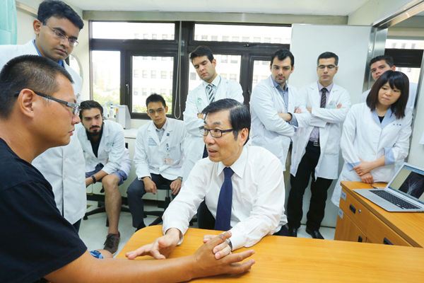 Figure 3 :   Foreign doctors gather round as Wei conducts his teaching outpatient clinic.