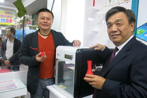 XYZprinting董事长沈轼荣（左）展示自家XYZPrinting。（图/陈韦哲摄）